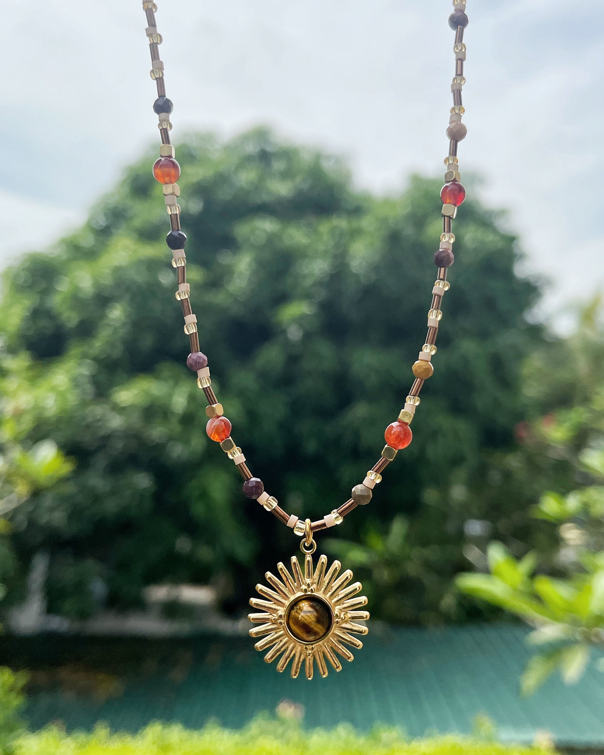 Gold sunburst necklace with earthy tones and natural stone center