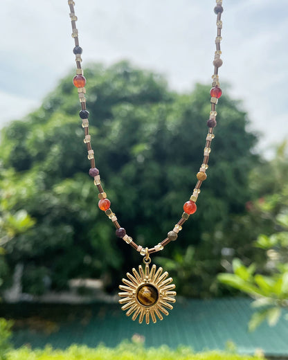 Gold sunburst necklace with earthy tones and natural stone center