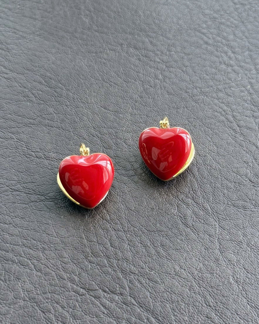 Red enamel heart earrings on leather background
