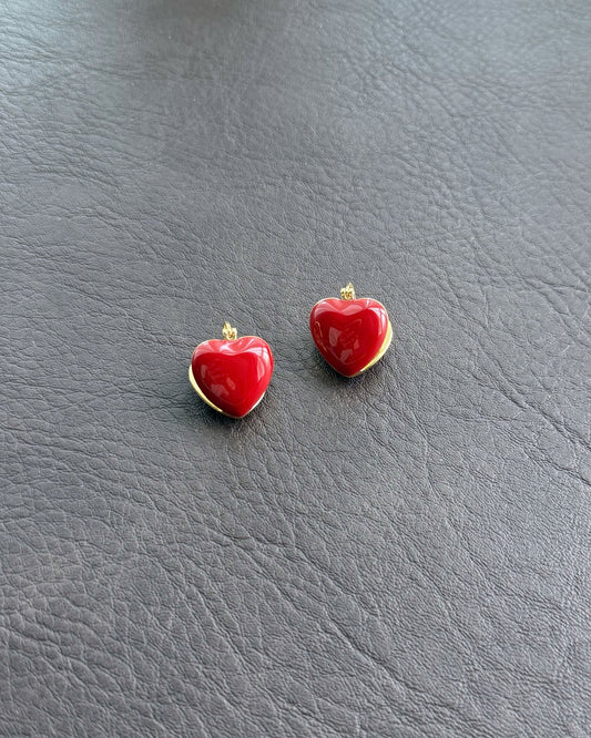 Red enamel heart earrings on leather background